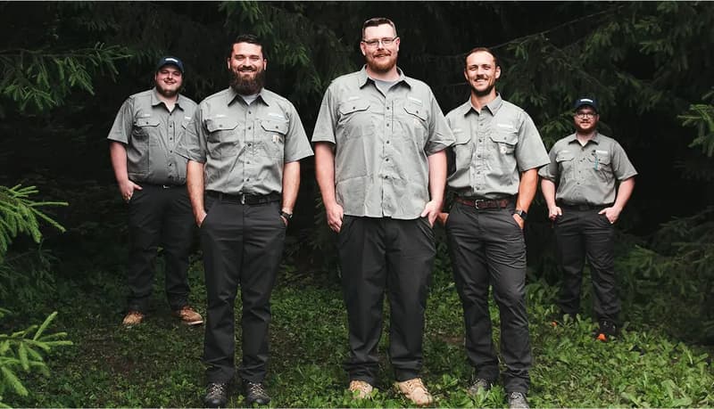 Five crew members in uniform standing in woods